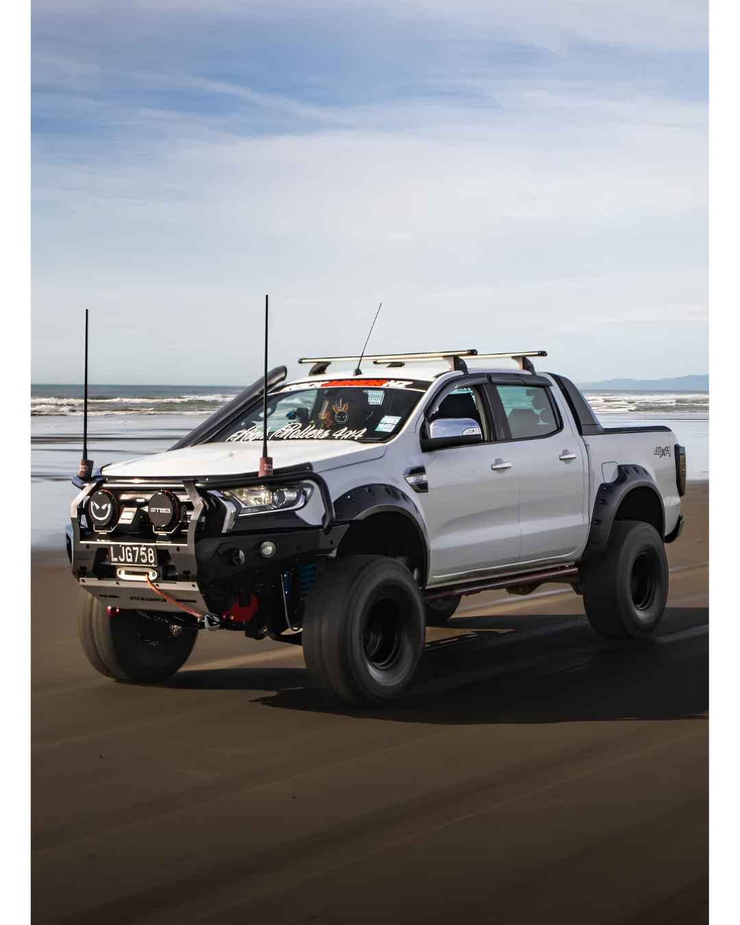 4WD white ute with AT tyres, bull bar, on beach, driving off-road