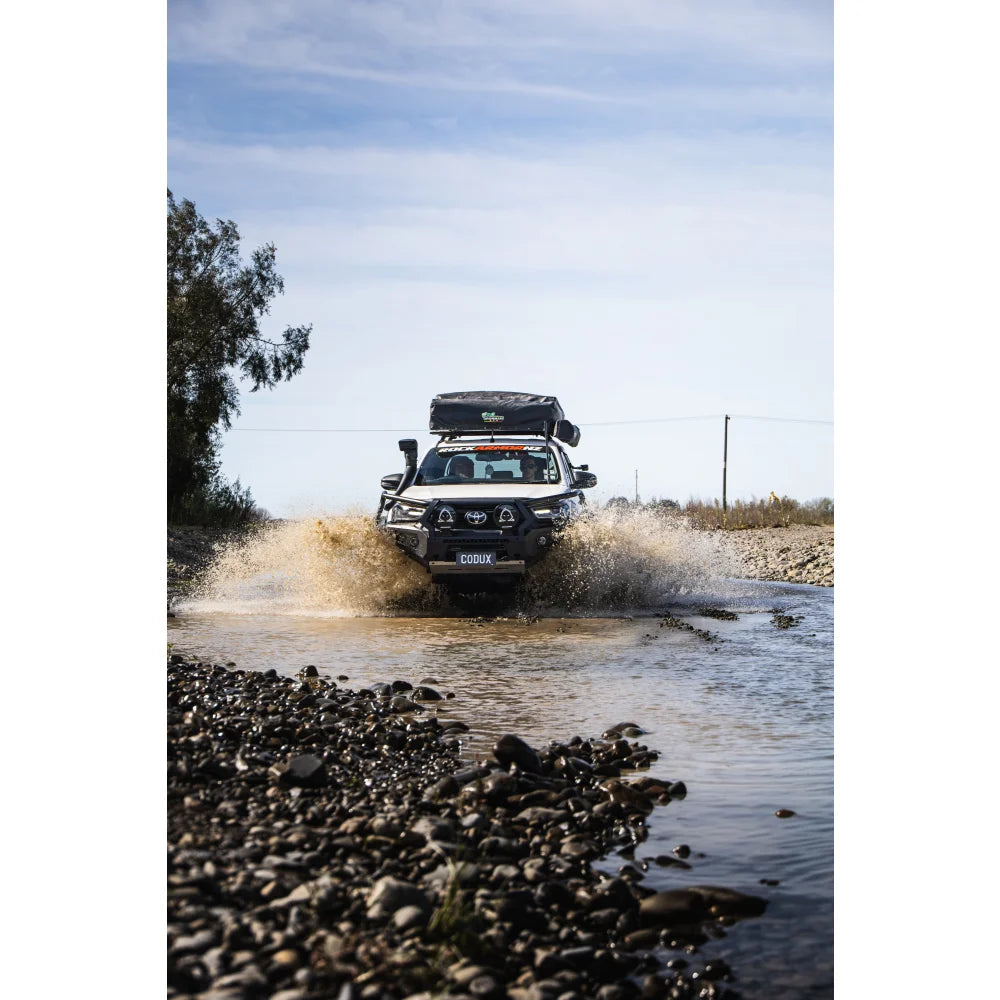 White off-road truck with steel hoop bull bar and driving lights navigating water