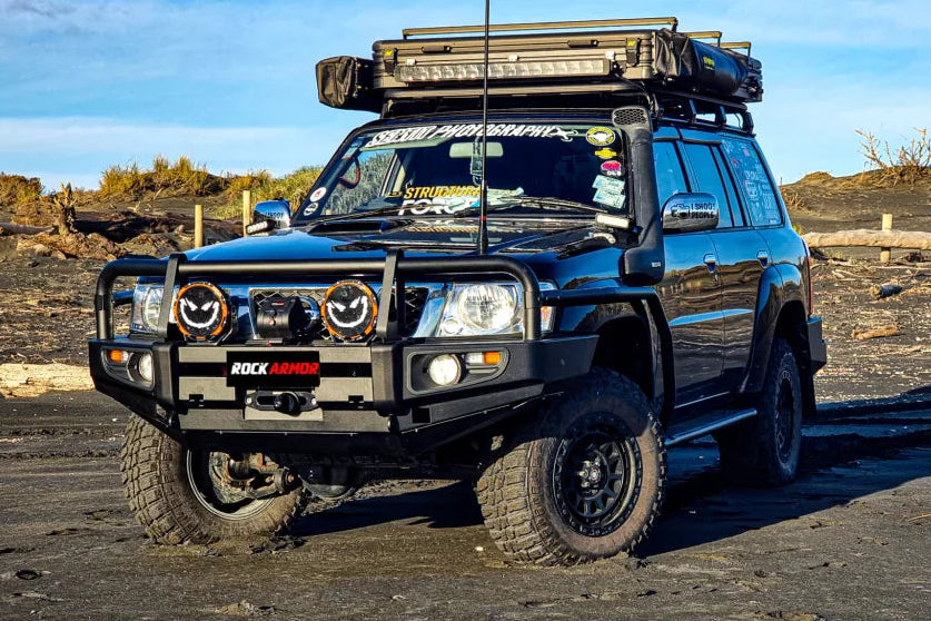 Black off-road vehicle with roof rack showcasing Rockarmor premium steel bullbar with fog lights
