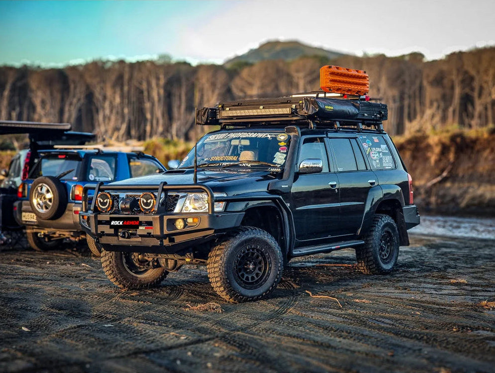 Black off-road vehicle featuring a premium steel bull bar with fog lights for Nissan Patrol GU4